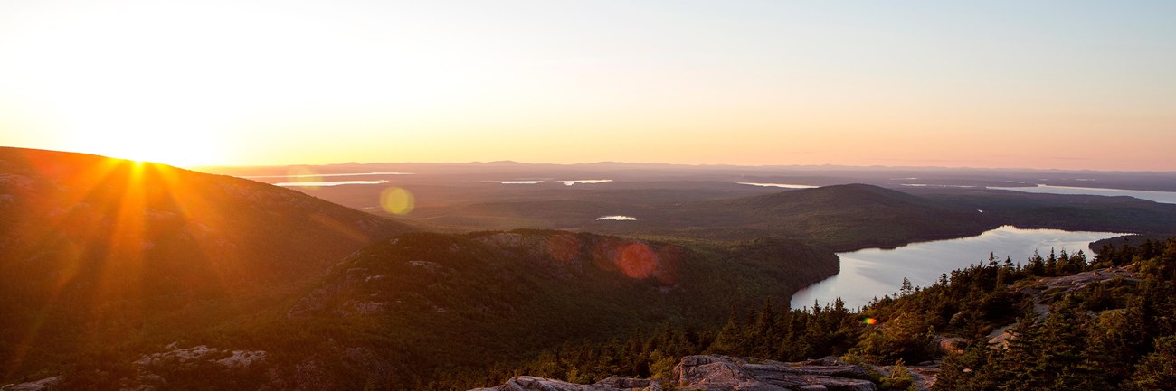 view of a lake at sunset from a mountain summit