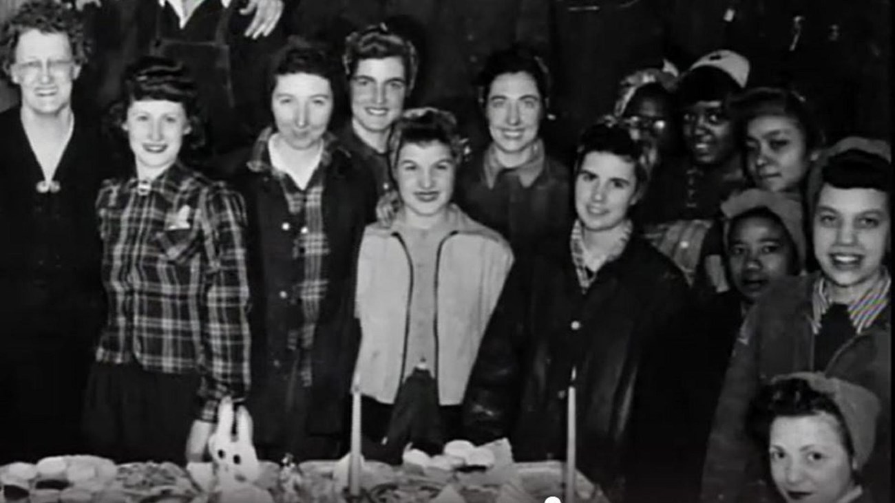Group of women Navy Yard workers standing side by side, smiling towards the viewer.