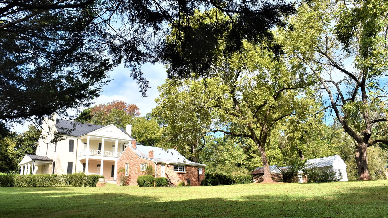 A large plantation house surrounded by smaller brick buildings and trees
