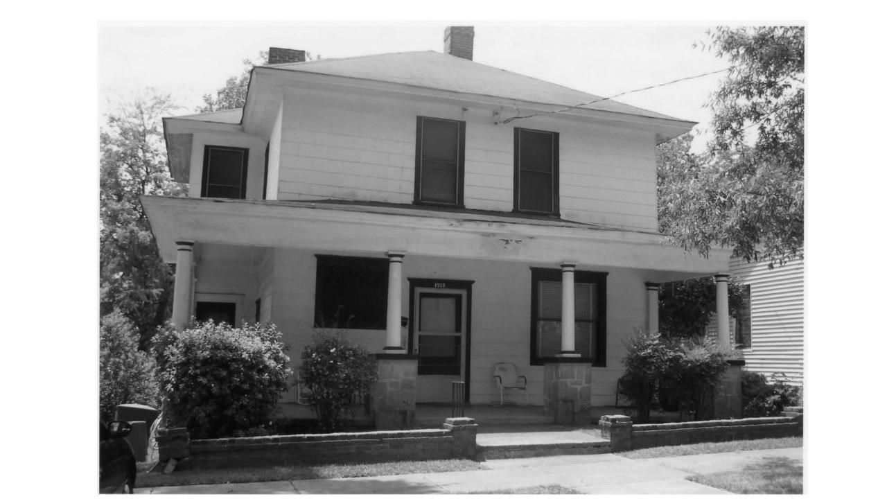 two story house with a wrapped full length porch with steps leading up to the entrance.