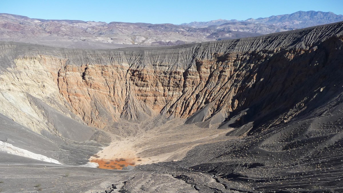 A 600 foot multi-hued crater in the desert rock.