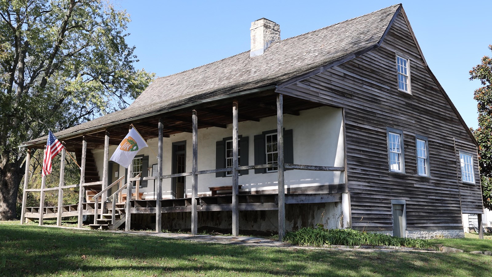 A house with a covered front porch, white front, plain wood siding and shingles.