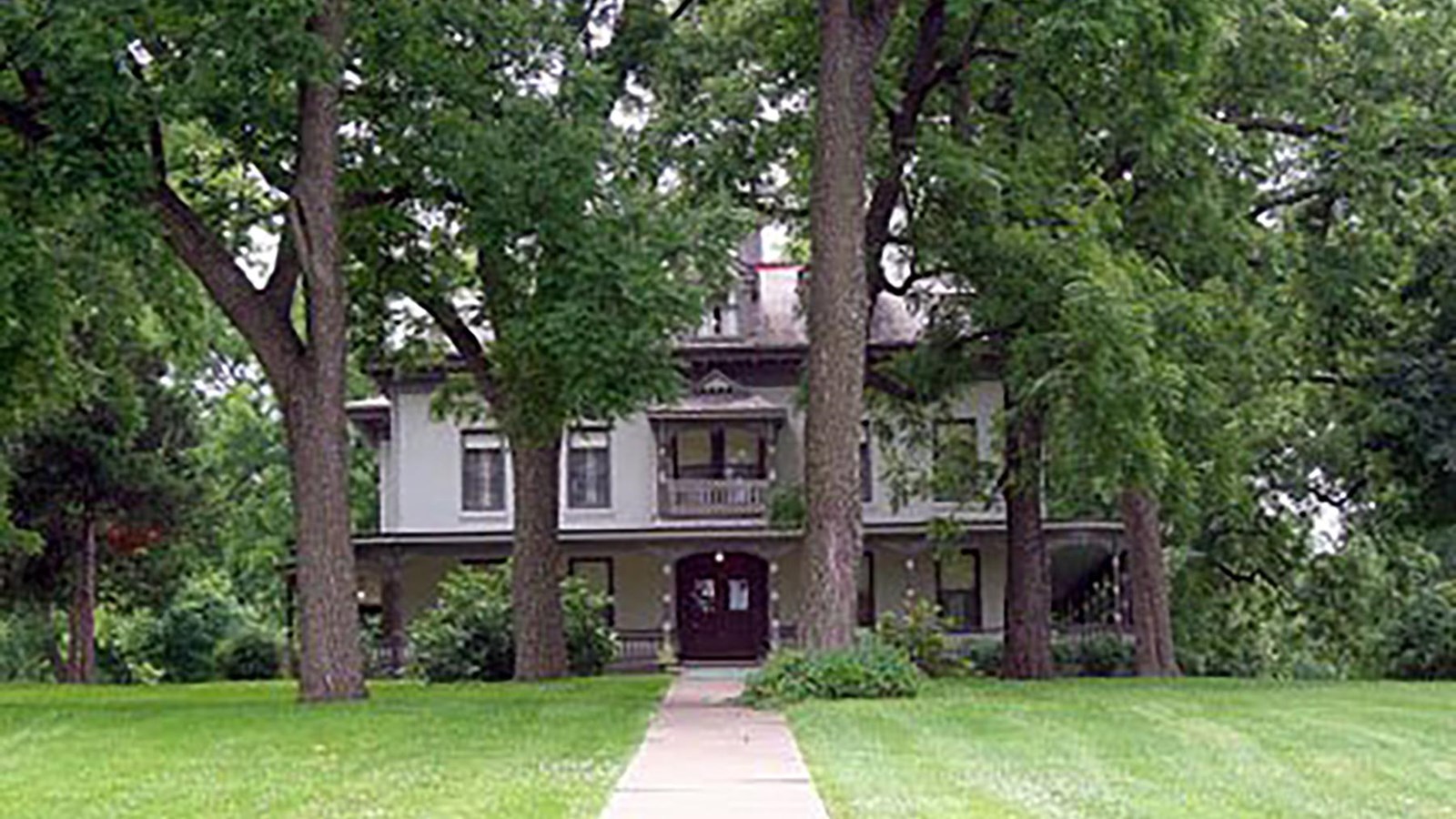 A large historic estate is peeking out behind large trees.