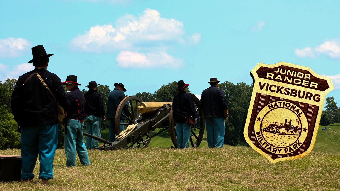 Several men dressed in civil war era uniforms stand near a cannon. An image of a wooden badge