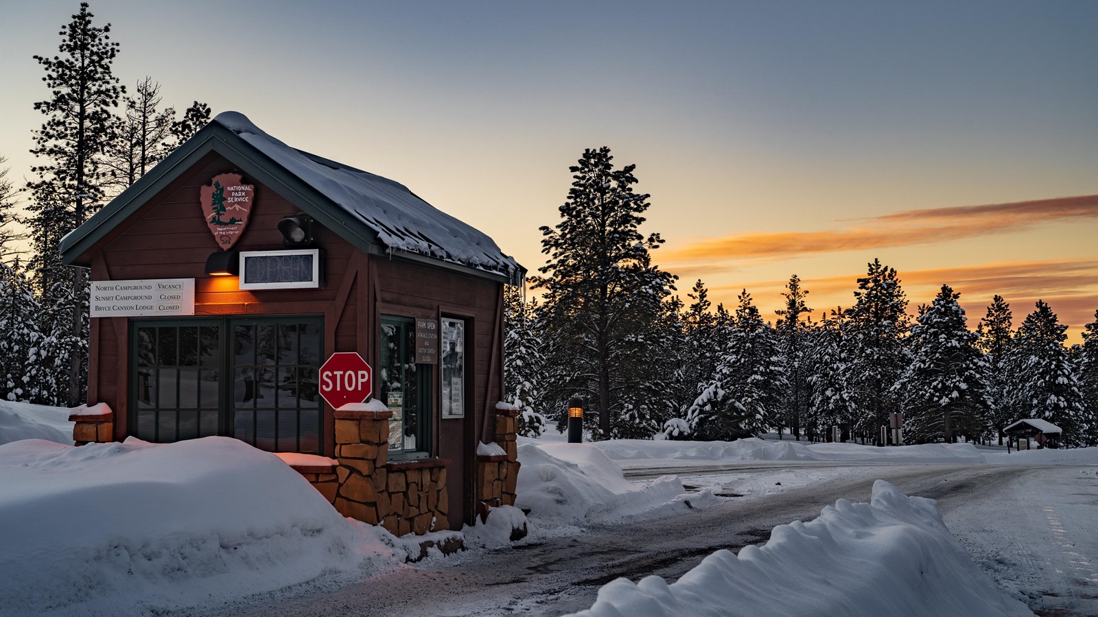 A brown wooden fee booth covered in snow