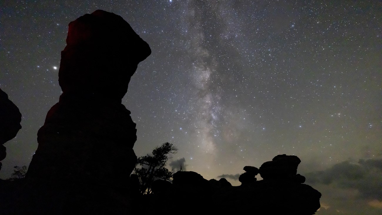 stars and milky way above a large rock formation
