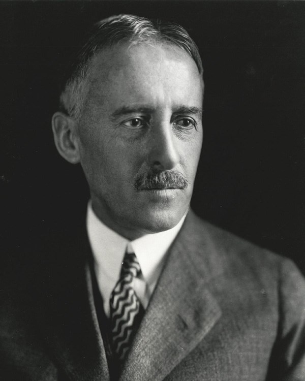 Black and white photo of a middle-aged man with a mustache wearing a suit.