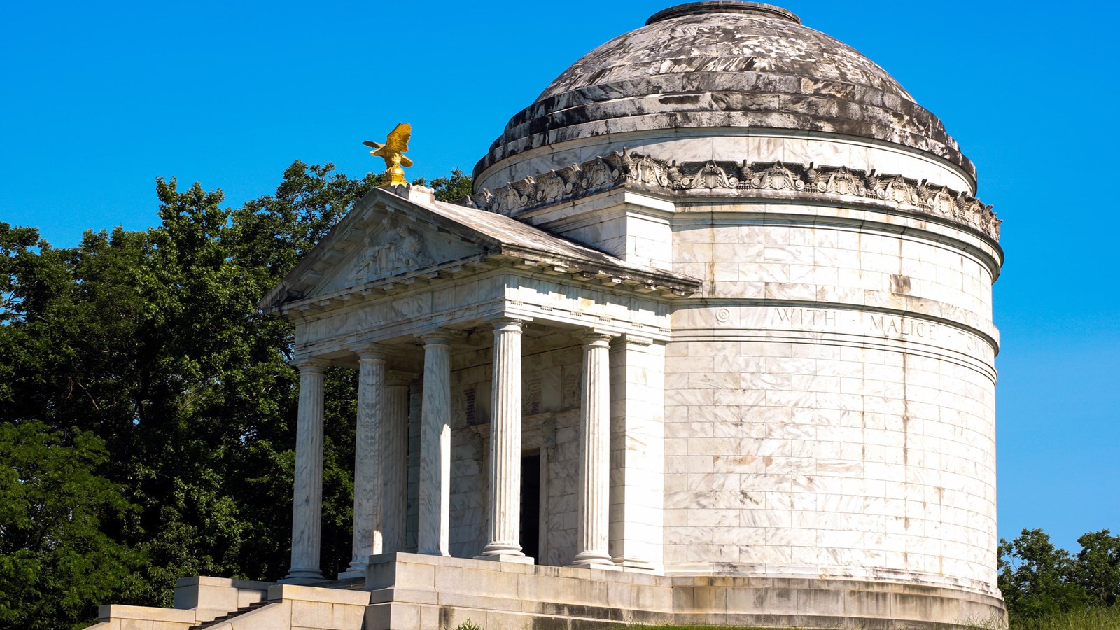 A side profile view of the round granite memorial with four large columns topped by a peak.