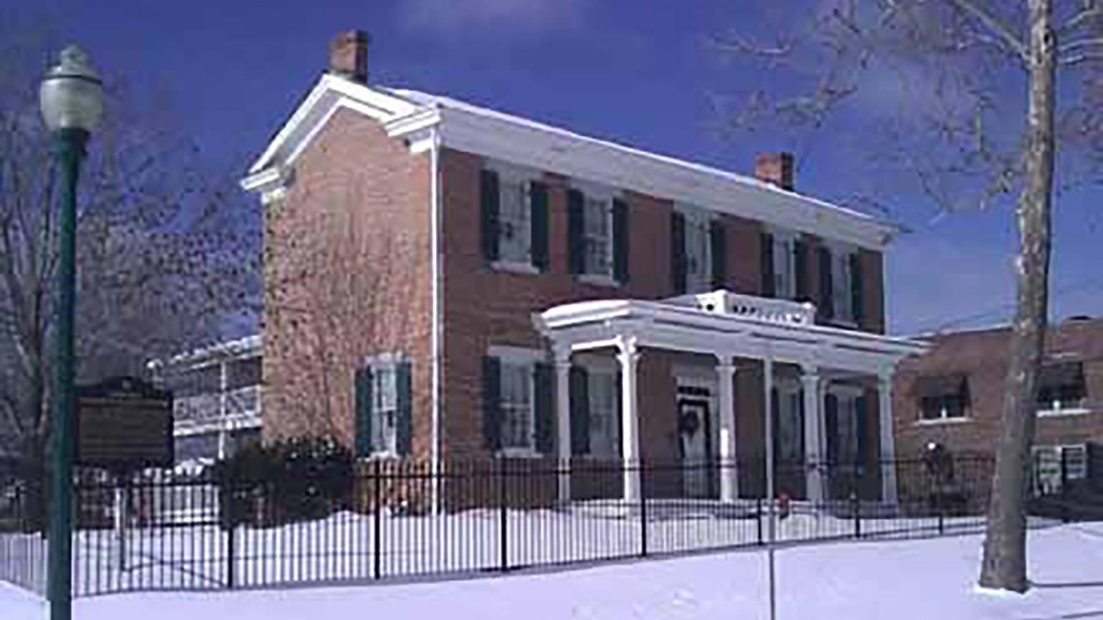A large two-story brick historic home with a white front veranda.