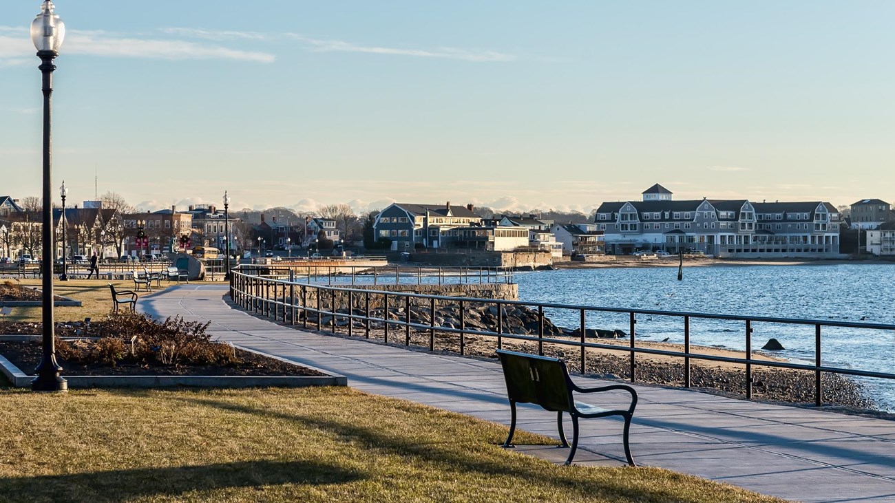 Boardwalk with benches overlooking body of water under blue sky