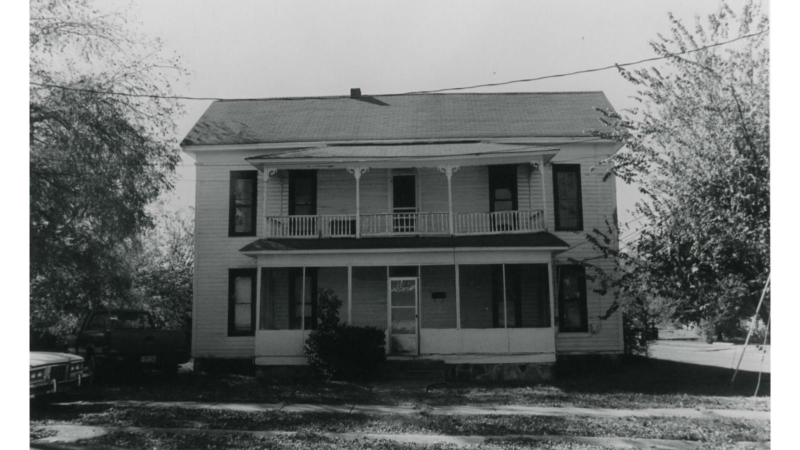 two story symmetrical house with a screen porch on the ground level and an open porch on the second 