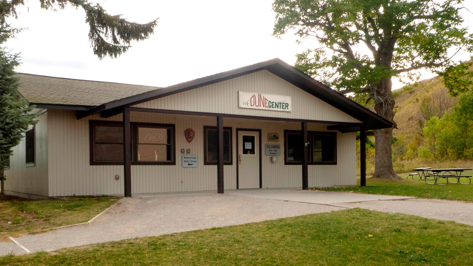 A beige-colored building with a covered porch and two paths converging at the porch.