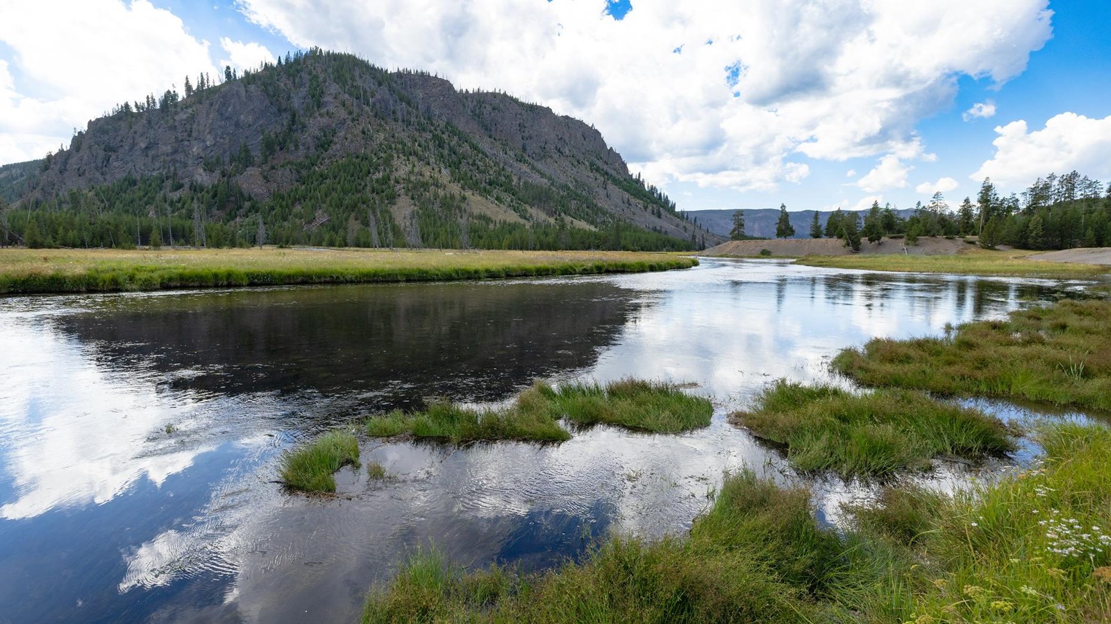 A mountain is reflected in a river located at the base of it.