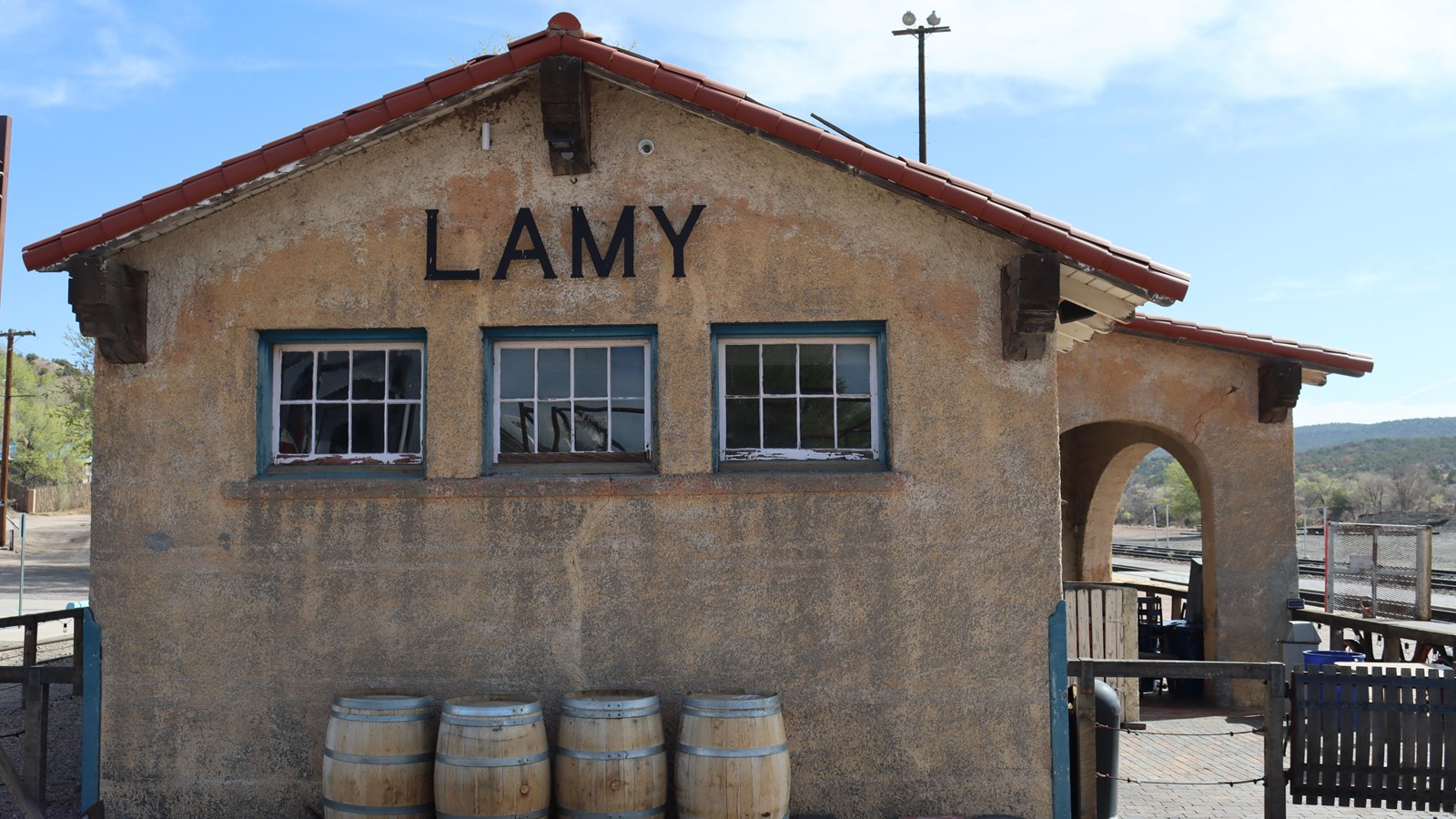 A cement building with a red tile roof. Above three windows text reads, 