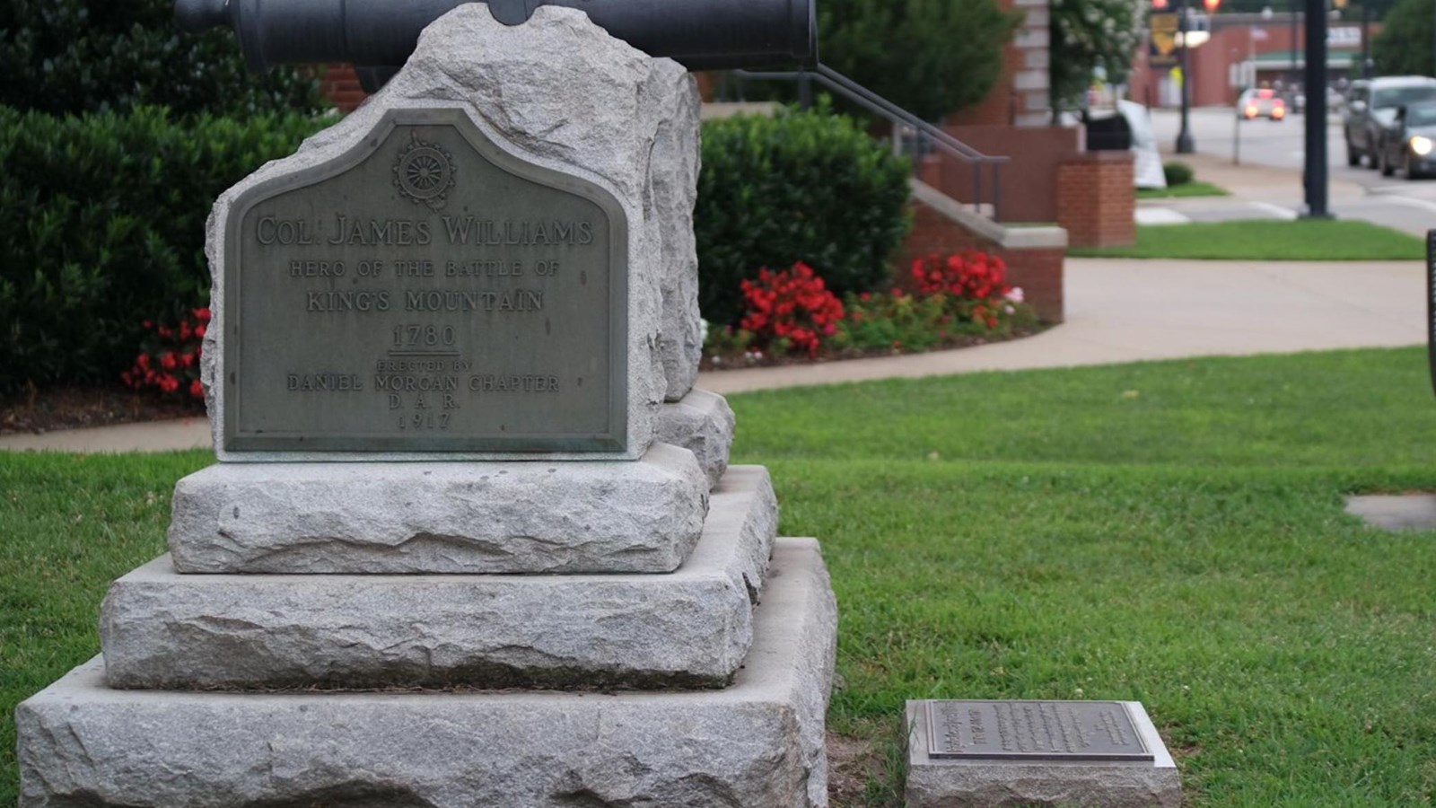 A gravestone is marked with Col James Willams with a city in the background.