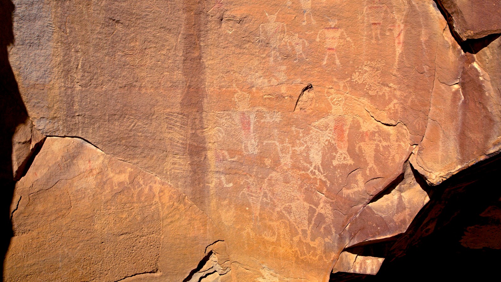 A large rock face with a variety of designs etched into the rock.