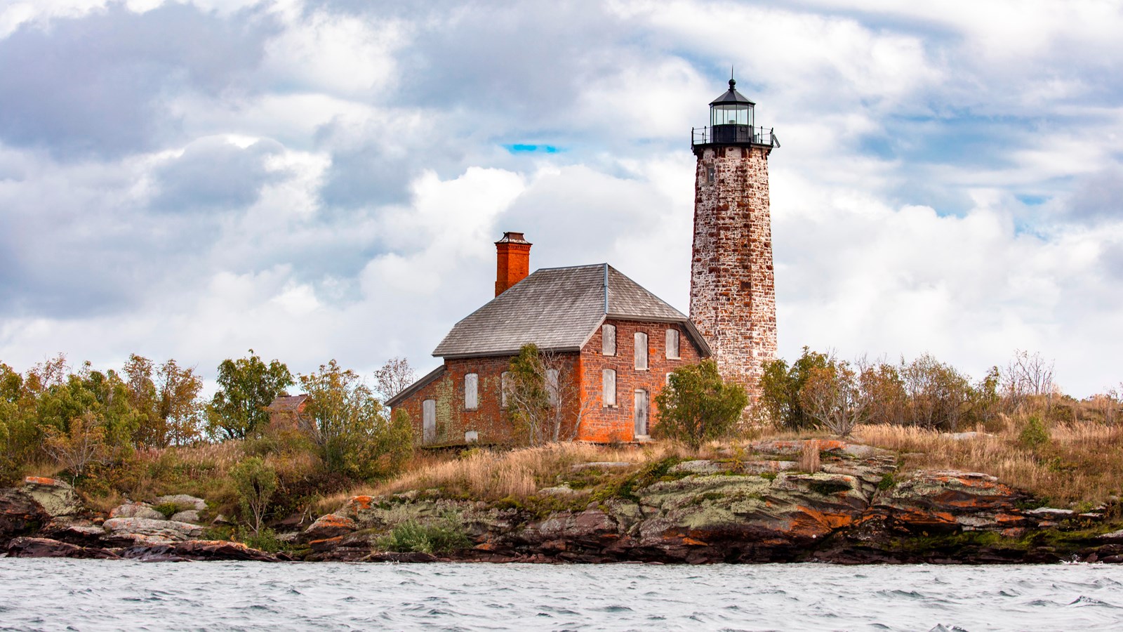 lighthouse sitting on rocky Menagerie Island on a blue sky day