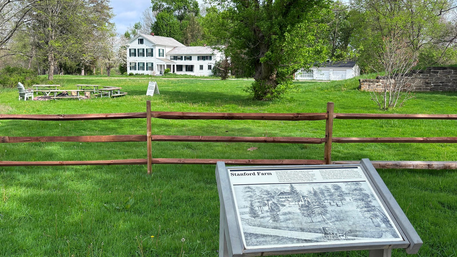 Two-story white house in the distance behind a graphic panel titled, Stanford Farm.
