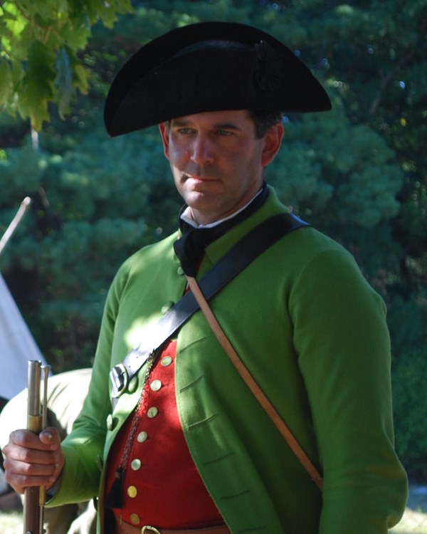 Revolutionary War militia soldier in a light green coat, red vest and breeches