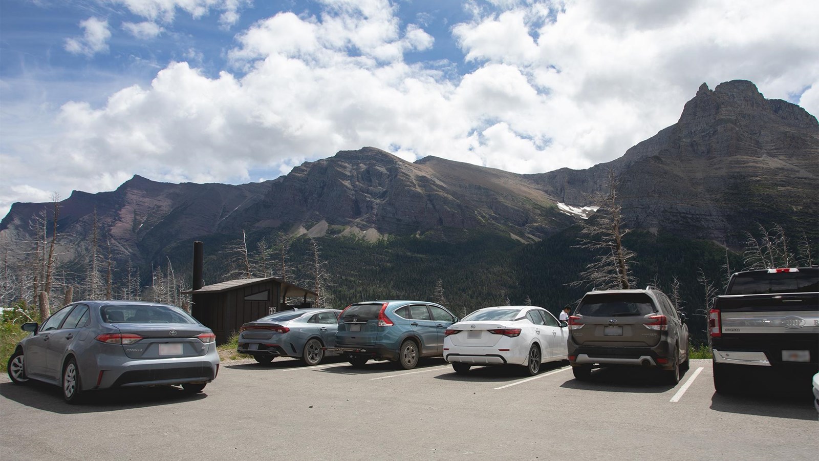 Cars parked at a parking lot surrounded by mountains