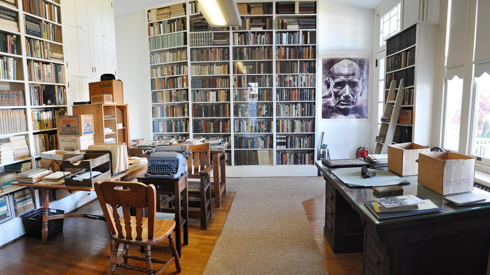 image of a home office with walls lined with full bookshelves, desks and a typewriter.