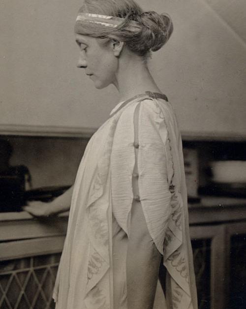 Side view of woman in classically inspired costume including glimmering headband.