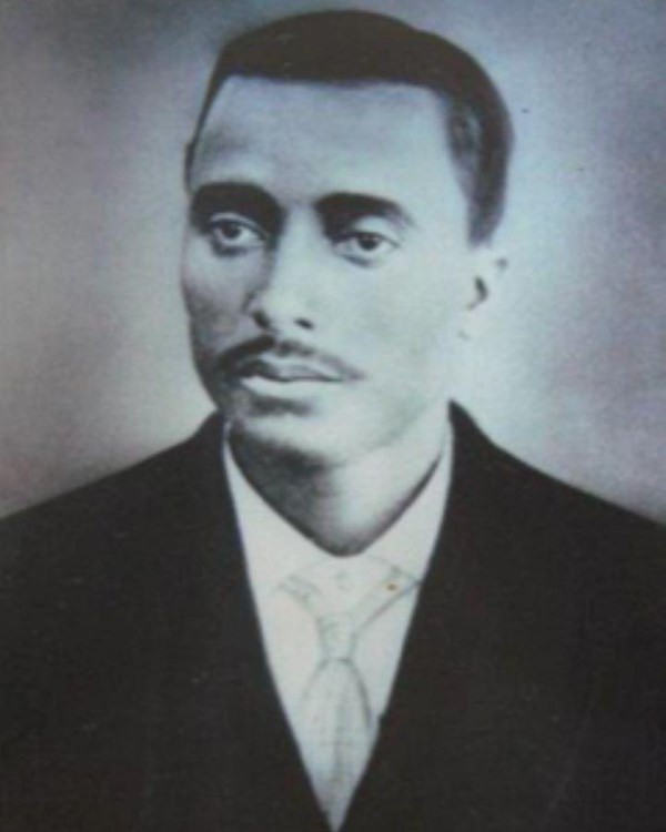 Black and white portrait of a young black man with a mustache, close cut hair, and suit with tie.t
