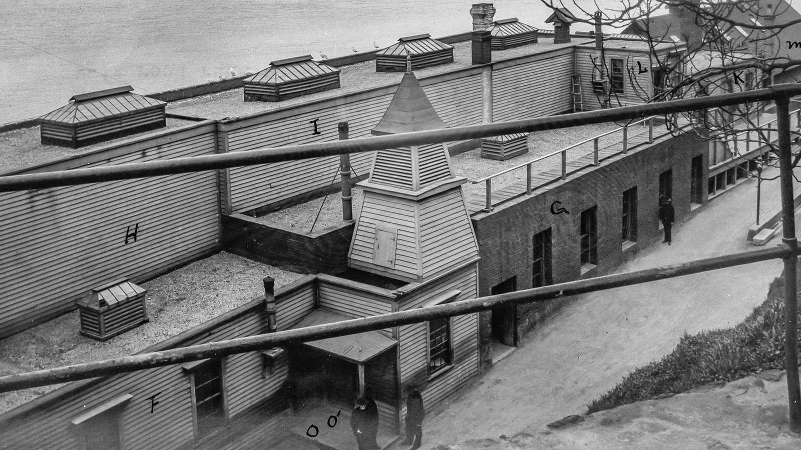 Black and white image looking down at the Lower Prison building, guards are standing outside.