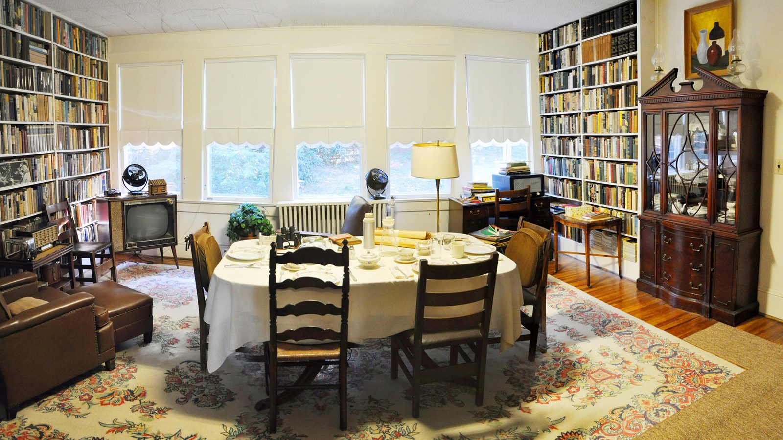 image of a dining room with a table and chairs and 2 walls lined with bookshelves.