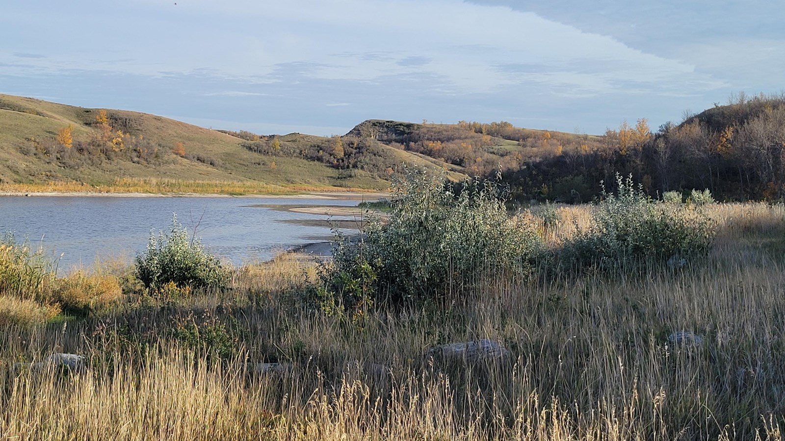 small body of water, rolling hills in background and grasses in forefront