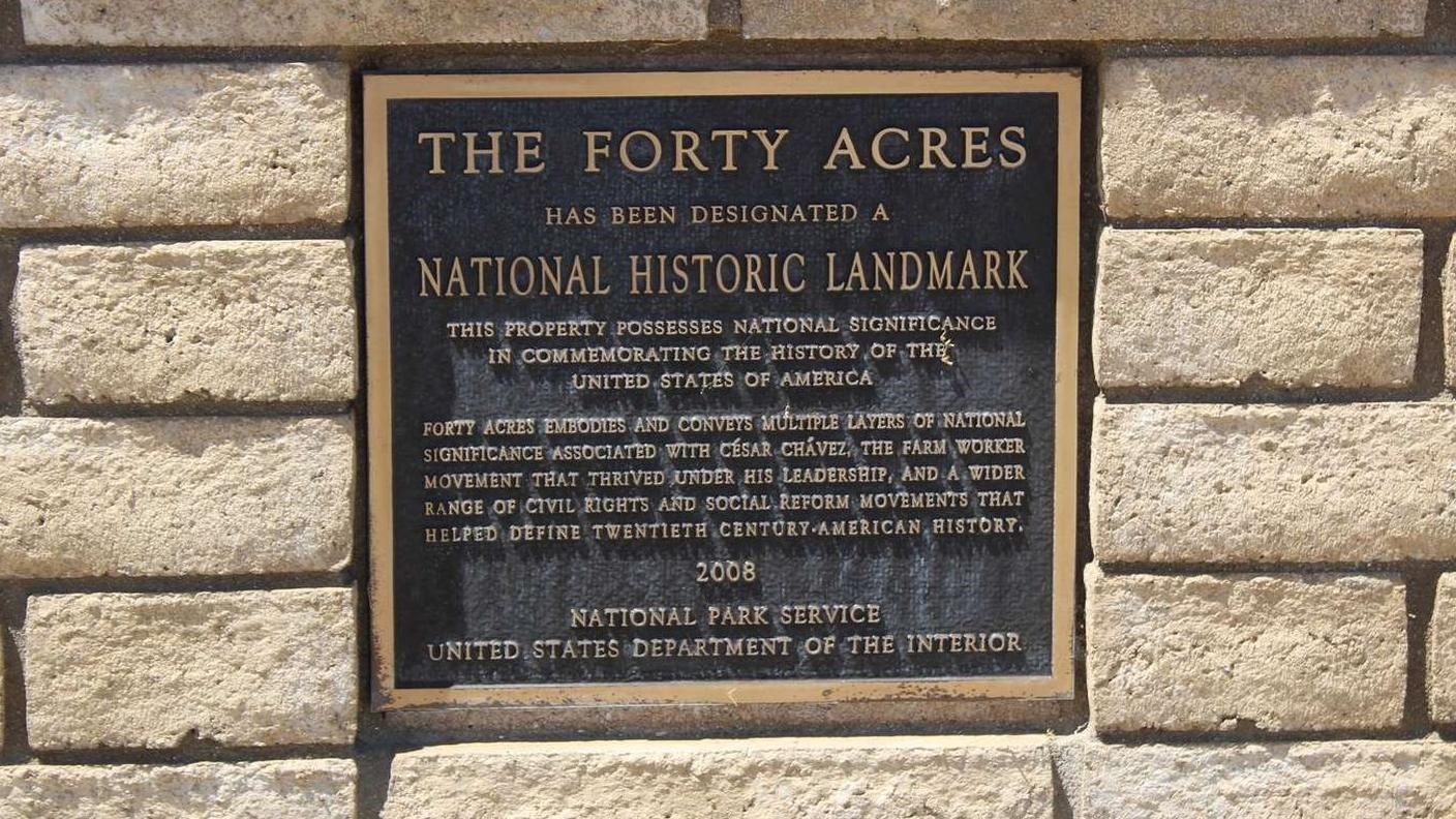 A metal plaque mounted in bricks. The plaque reads,