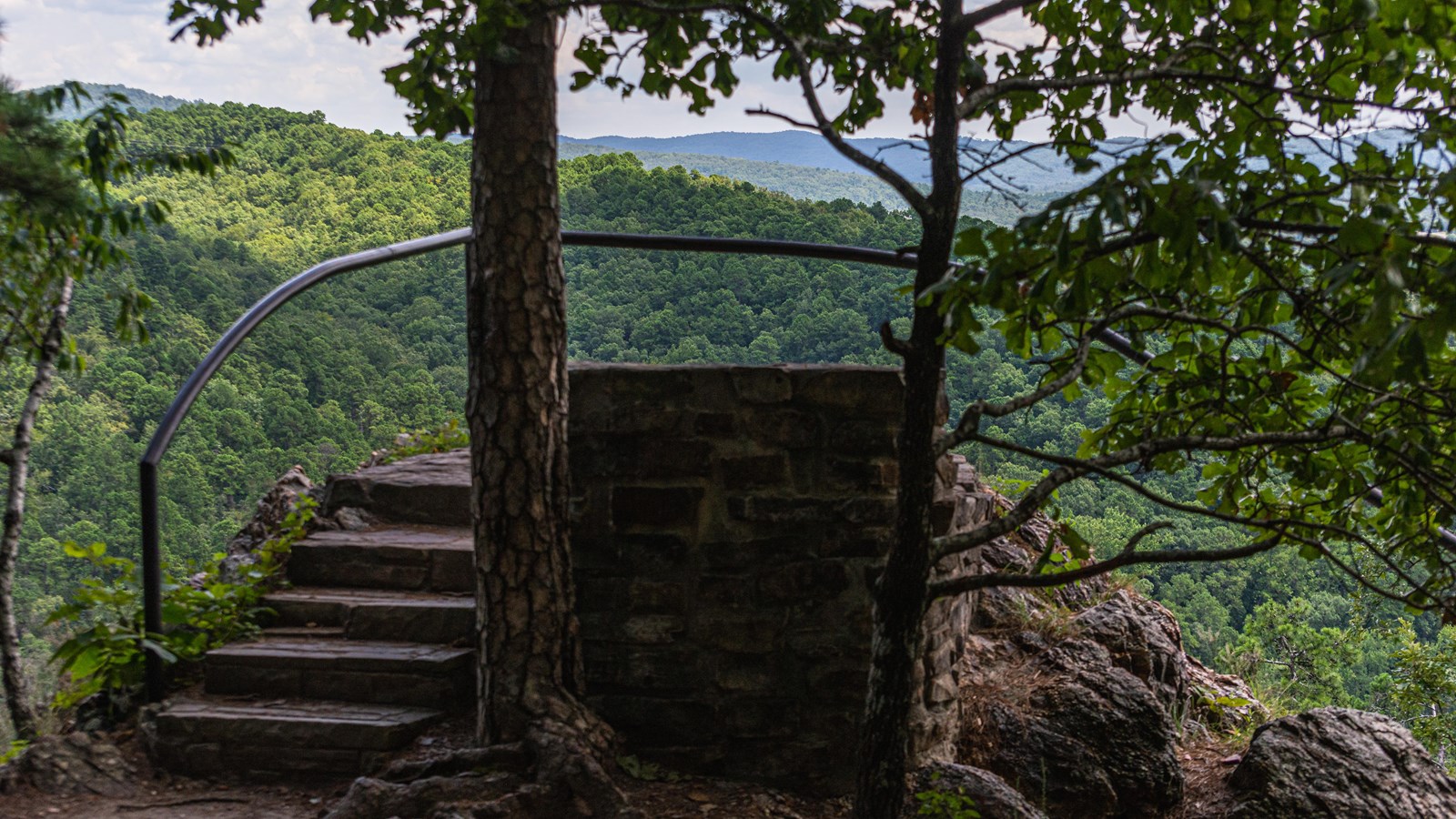A small set of steps leading to a railed overlook of hills