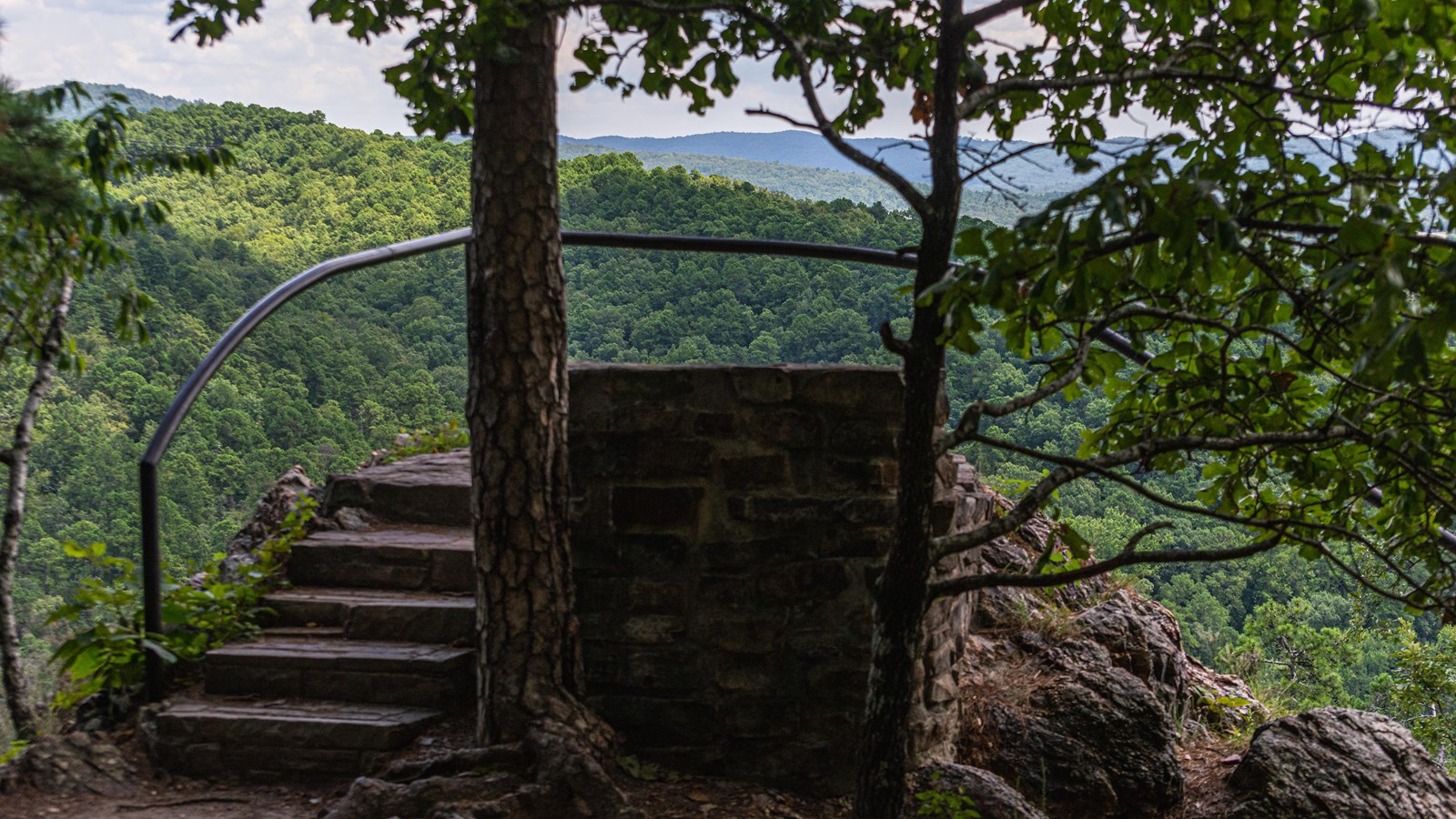 A small set of steps leading to a railed overlook of hills 