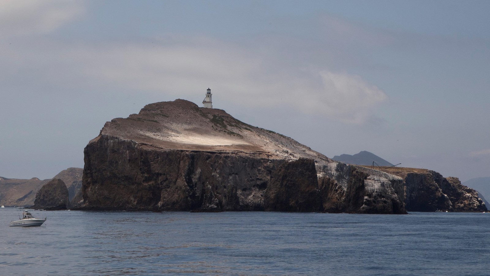 small boats next to island with lighthouse