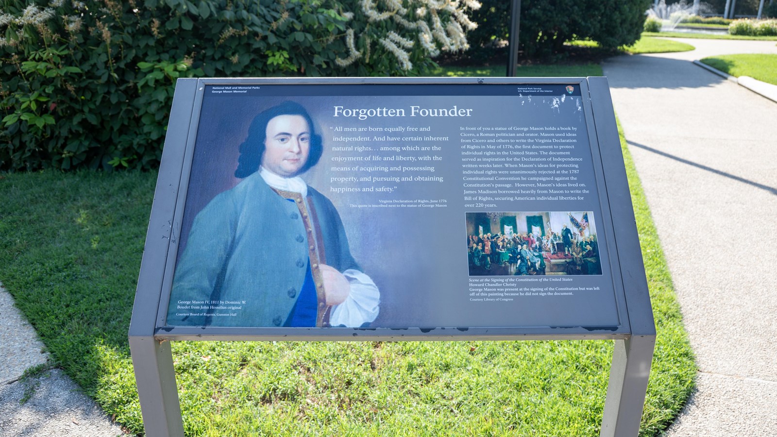 An information panel with images and text on a metal stand at the edge of a sidewalk.