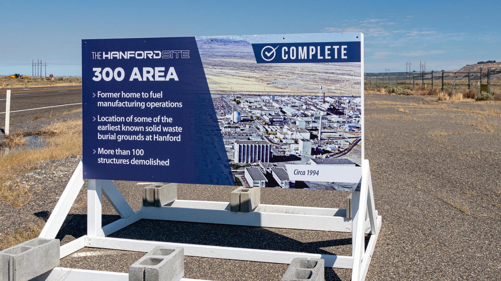 Large informational sign sits along a road and in front of an empty lot.