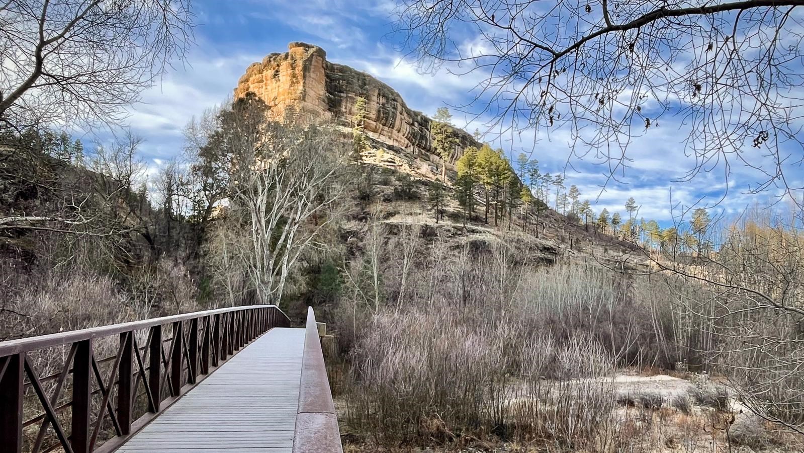 Bridge crossing a river with cliffs in the background.