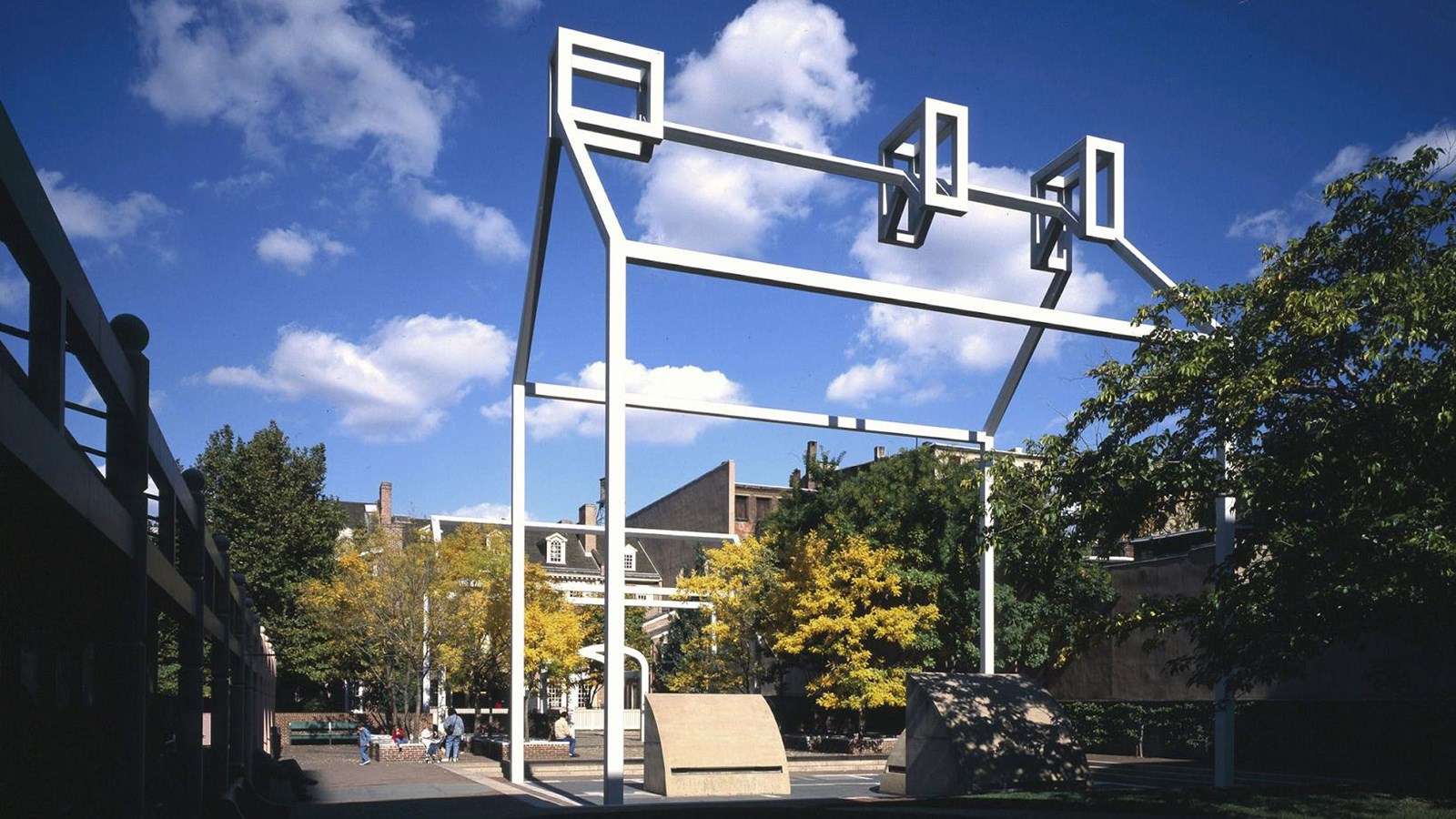 A color photo showing a white steel frame outlining the shape of a house set against a blue sky