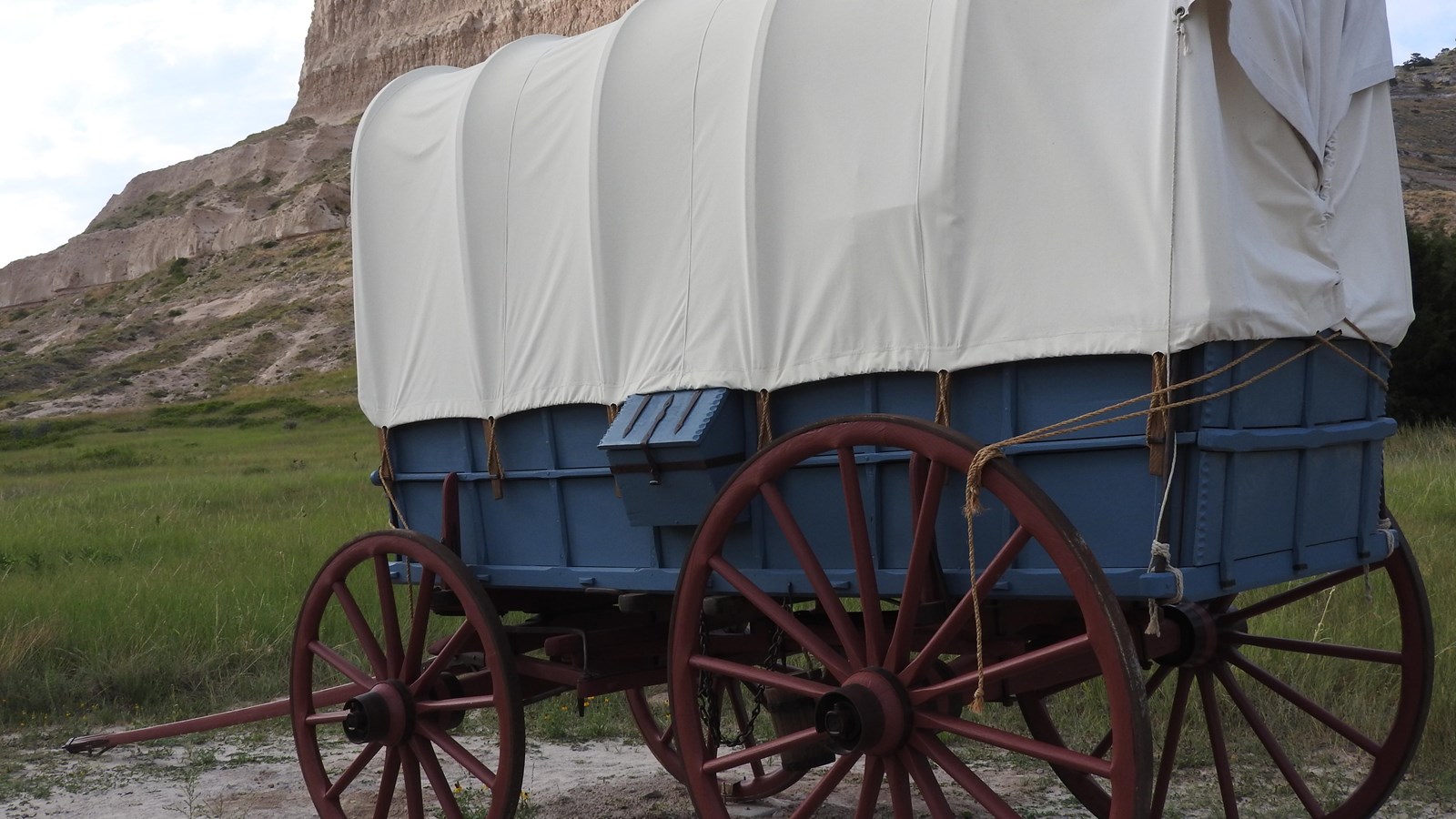 A Studebaker wagon is painted blue with red wheels and a canvas cover.