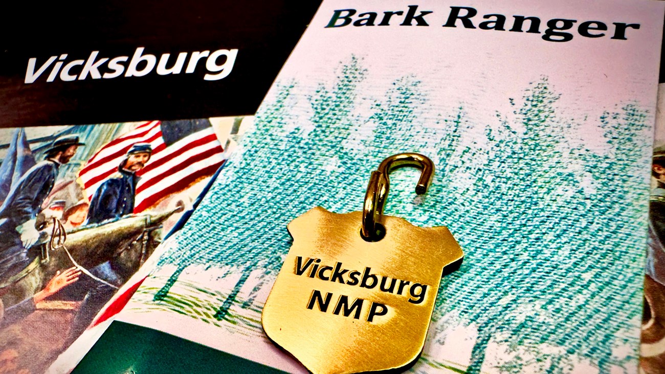 A gold dog tag that reads Vicksburg NMP