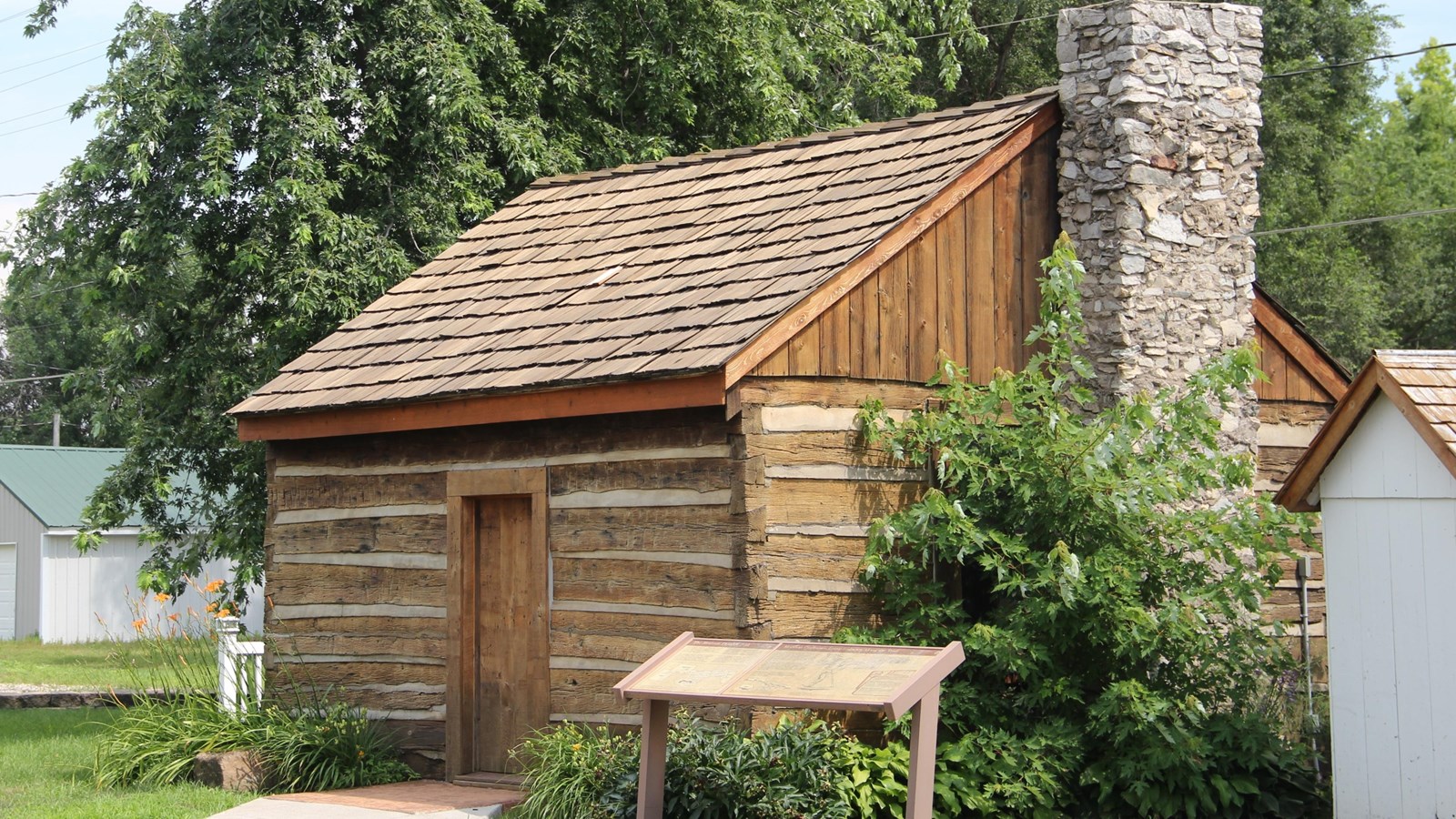 view of a rectangular, golden brown, single-room cabin built of hand-hewn, squared logs.