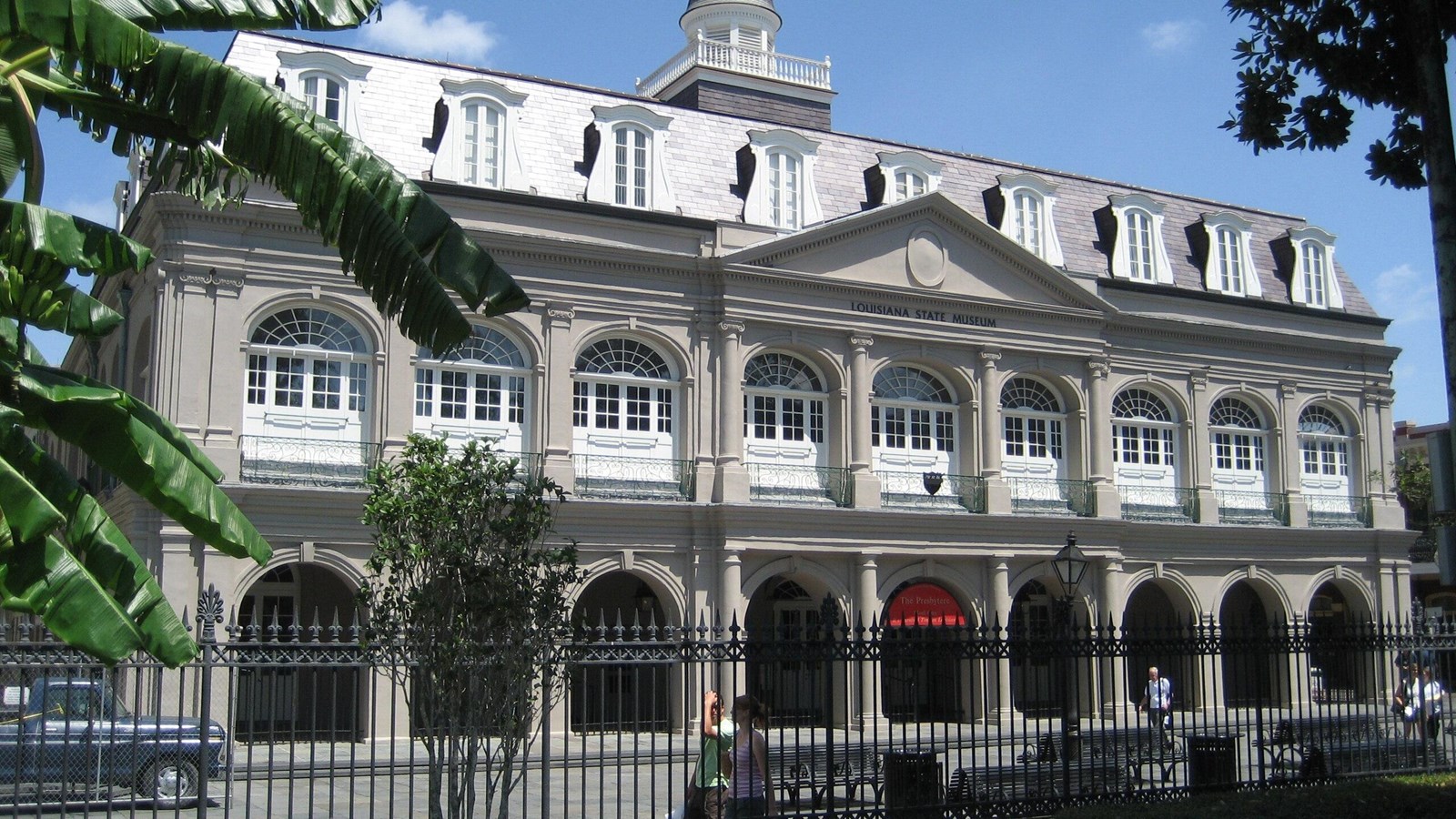 White and light grey three story building with arches over windows on 1st and 2nd floor