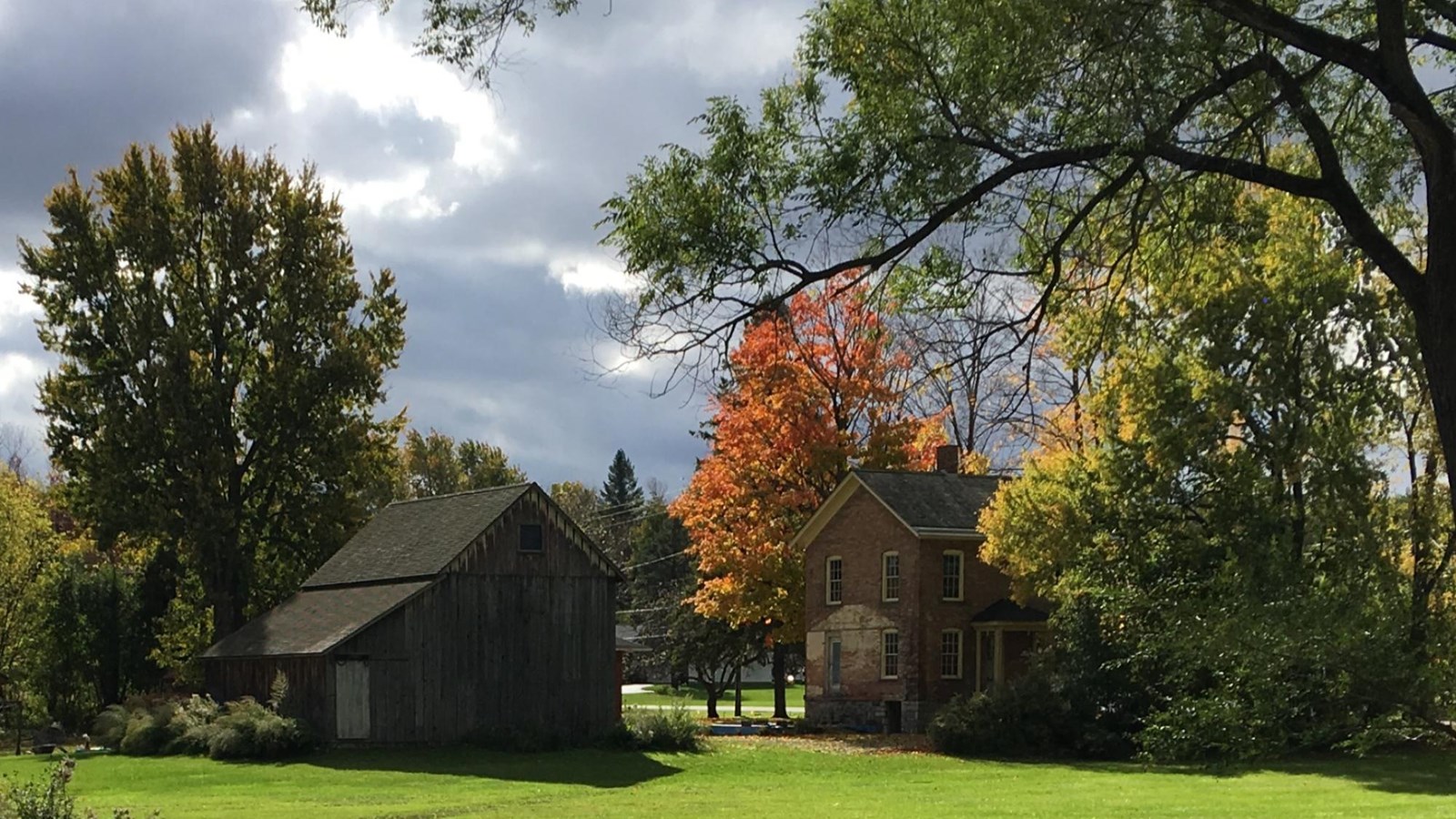 Tubman\'s brick house and wood barn with trees in fall. 