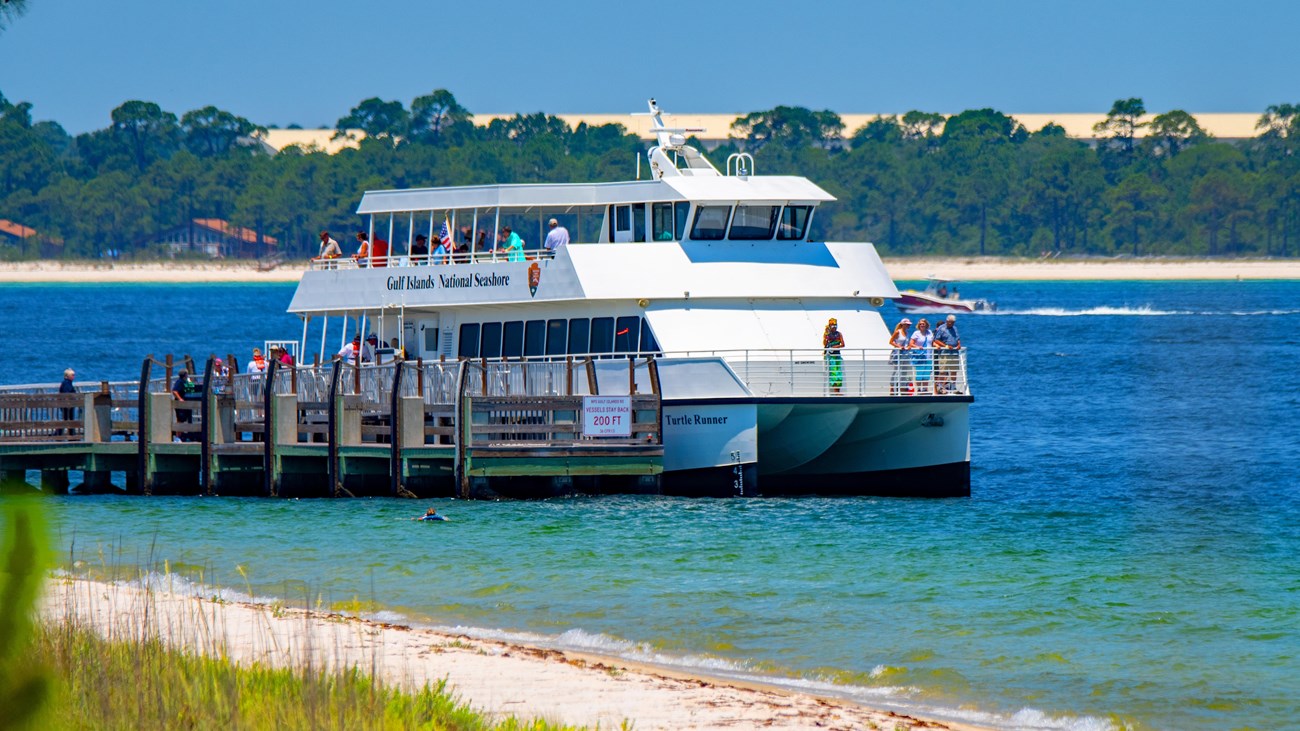 A ferry waits a dock in bright blue water.