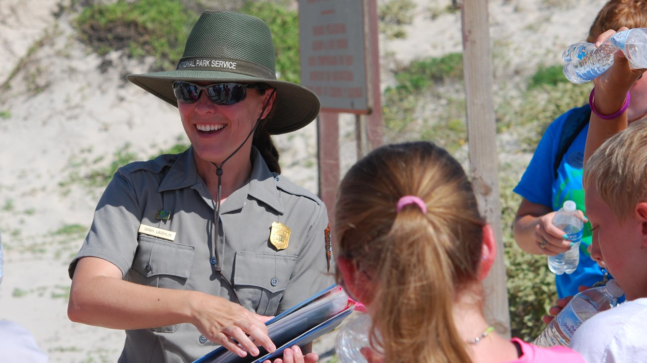 A park ranger smiles as she talks to park visitors.
