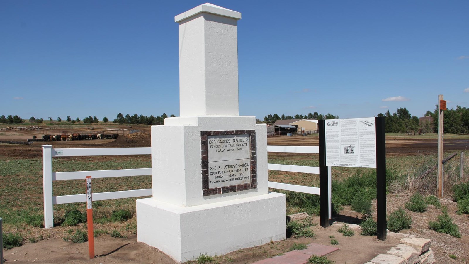A large stone marker with a plaque in a field.