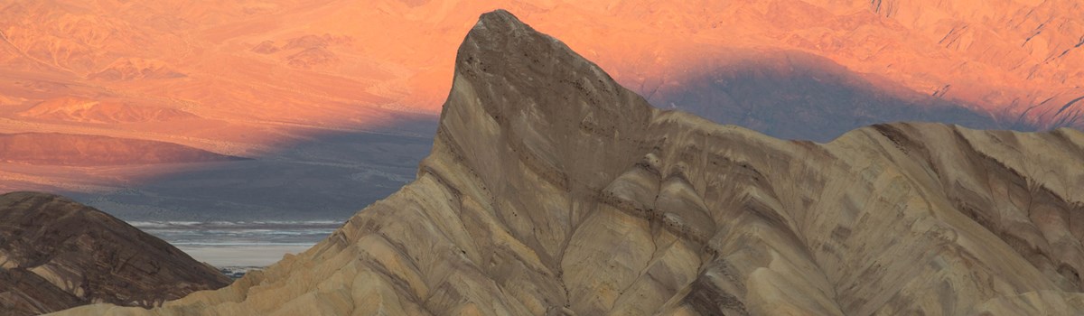Highly eroded badlands at sunrise, with a distinct point in the distance.