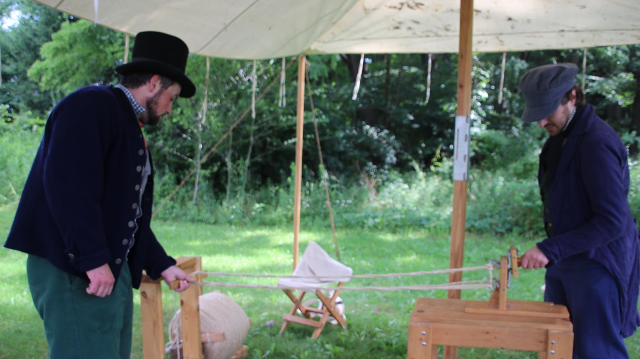 Two rangers in period clothing doing a rope making demonstration.