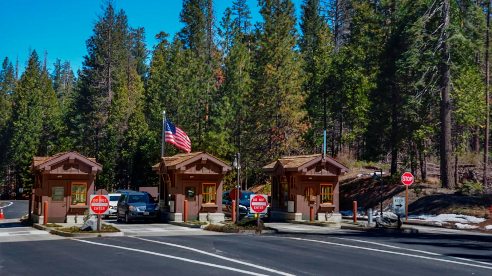 Three small wooden buildings at the entrance with the American flag on a pole