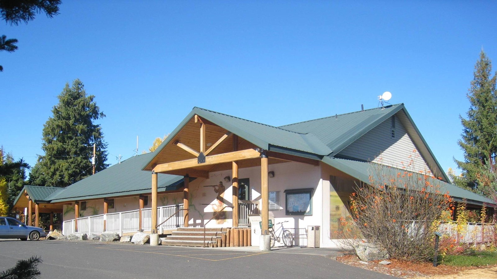 A white building with wooden columns with murals along the sides. 
